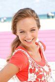 Portrait of pretty woman wearing orange-shirt and white fishnet top, smiling, close-up