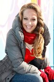 blonde Frau lacht in die Kamera Winterjacke und Handschuhe