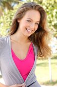 Portrait of beautiful blonde woman wearing pink and gray top, smiling