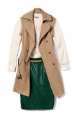 Beige trench with detachable sleeves and green leather skirt on white background