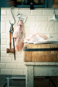 A leg of pork on a hook and a goose on a wooden board in a butcher's shop