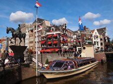 Equestrian monument and ferry in canal in Rokin street, Amsterdam, Netherlands