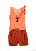 Orange top with bow taupe, sun glasses and red shorts on white background