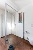 Bathroom with glass shower cabin and toilet seat on wooden floor