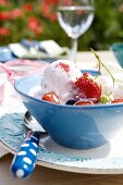Blue bowl of ice-cream with strawberries and blueberries on plate