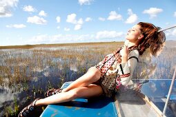 Woman dressed in ethnic style relaxing on boat in Everglades, Florida, USA