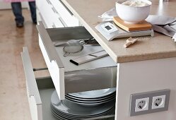 Close-up of glossy drawers with plates and kitchen utensils