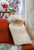 Hot water bottle under creme knitted cover with fur