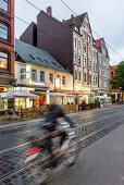 View of cyclists and cafes on street in Linden, Hannover, Germany
