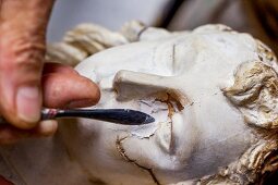 Close-up of restoring angel figure being repaired