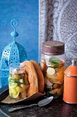 Pickles in glass jars and sesame bagels on table