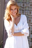 Portrait of beautiful blonde woman wearing white tunic blouse, smiling