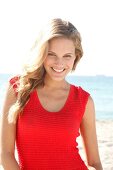 blonde Frau im roten Top am Strand, lacht im Kamera
