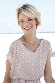 Portrait of happy blonde woman with short hair wearing polka dots dress, smiling