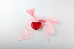 Close-up of pink ribbon with heart on white background