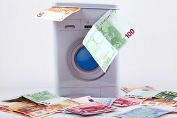 Geldwäsche, Geld und Waschmaschine in Miniaturfomat