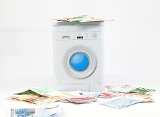 Geldwäsche, Geld und Waschmaschine in Miniaturfomat