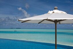 Parasol at swimming pool in front of sea, Dhigufinolhu island, Maldives