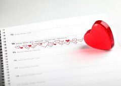 Red glass heart on calendar with date of 14th February