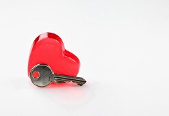 Close-up of red heart shaped glass and key on white background representing valentines day