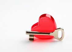 Close-up of red heart shaped glass and key on white background representing valentines day