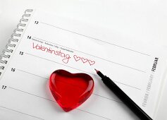 Red glass heart on calendar with date of 14th February