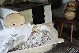 Brotlaib in Gärkörbchen aus Holz, zugedeckt, Ofen