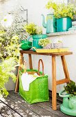 Teak bench, herbs in enamel containers and raffia bag on balcony