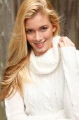 Portrait of beautiful blonde woman with long hair in white turtleneck sweater, smiling