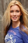 Portrait of attractive blonde woman with long hair wearing blue top, smiling