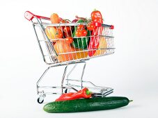 Shopping cart with vegetables and fruits on white background