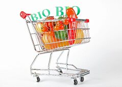 Shopping cart with vegetables and fruits on white background