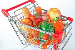 Shopping cart with vegetables and fruits on white background