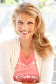 Portrait of attractive blonde woman wearing bright jacket over pink top, smiling