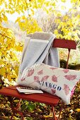 Printed linen cushion on folding chair in autumnal garden