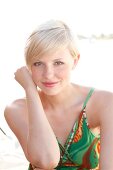 Blonde woman with short hair in a green dress on the beach