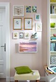 A small picture gallery of drawings with a television on the wall next to a bookshelf