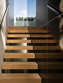 Narrow stairway with open wood steps wand black stone tiles on the wall