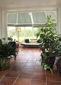 A view into a conservatory with a daybed and terracotta tiles