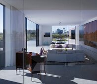 South American house with view across wide landscape through glass walls of living room with sofas and elegant, curved cabinet