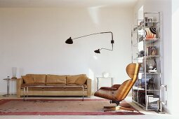Armchair and wall lamp in Bauhaus style in front of a light brown leather sofa in the corner of a living room