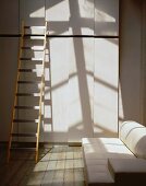 Ladder in front of a contemporary built-in cupboard and white leather couch