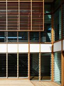 Wooden louvers in front of a house facade with adjustable glass louvers