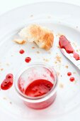 The remains of a croissant and jam on a plate