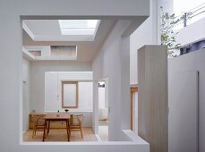 Schlichter Tisch mit Stühlen im Bauhausstil im modernen Haus mit Ausschnitten in Wand und Decke