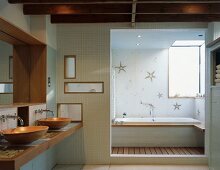 Washstand with wooden sinks and doorway to bathtub with starfish-patterned tiles