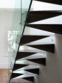 Back of made-to-measure steel staircase with glass balustrade and spotlights in wall