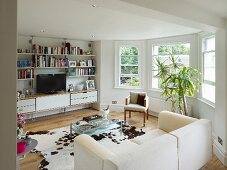 Modern living room with traditional bay window and cow skin rug in front of white sofa