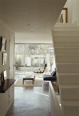Offenes Treppenhaus mit breitem Durchgang und Blick auf Sesseln im modernen Wohnzimmer