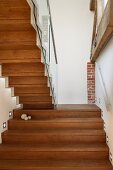 Rückansicht einer Holztreppe im renovierten Treppenhaus mit eingebauten Wandstrahlern